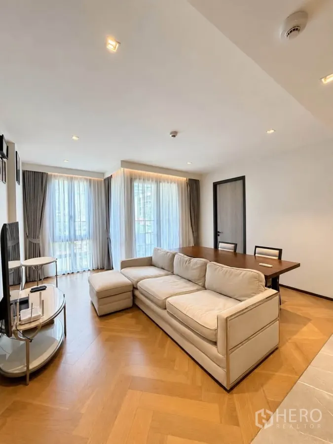 Condominium for rent or sale in Watthana, Bangkok - Corner living area with sofa beside a dining table and wraparound windows.