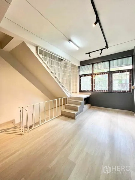 Home Office for rent in Khlong Toei, Bangkok - Open workspace beside stairs with track lighting and large windows.