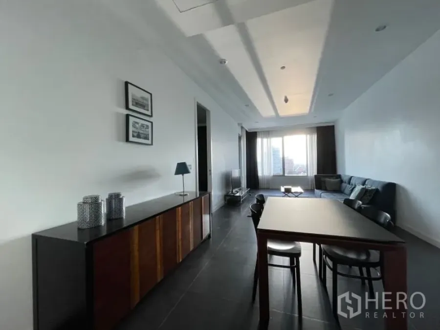 Condominium for rent or sale in Pathum Wan, Bangkok - Open-plan dining and living area with dark tile floors, recessed ceiling and wide window.