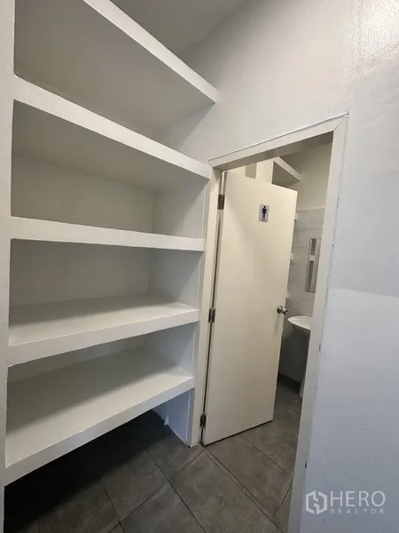 Retail Space for rent in Bang Rak, Bangkok - Built‑in white shelving beside a doorway leading to a private restroom.