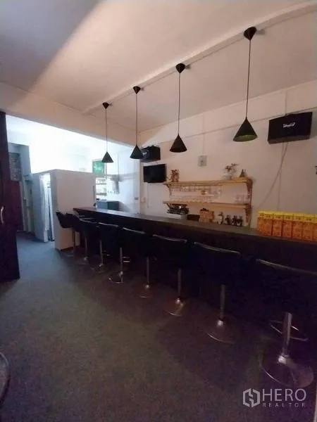 Shophouse for rent in Khlong Toei, Bangkok - Full-length counter with multiple stools in a white-walled bar interior.