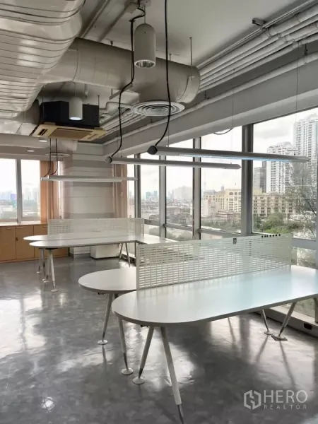 Office Space for rent in Khlong Toei, Bangkok - Corner workspace with white bench desks by wraparound windows overlooking Bangkok.