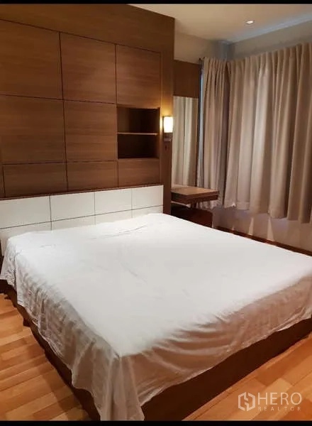 Condominium for rent - Primary bedroom with wood panel headboard, bedside lighting and curtained window.