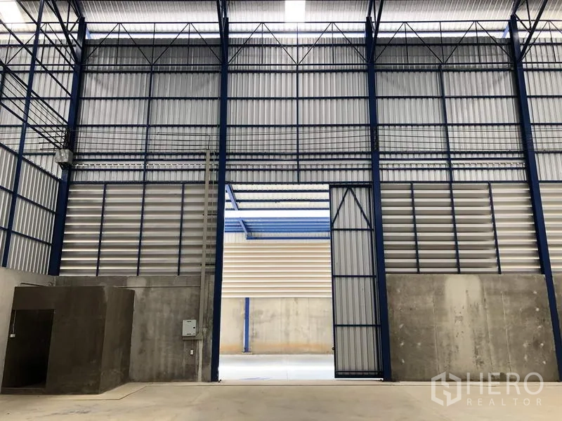 Factory for rent in Lat Lum Kaeo, Pathum Thani - High-clearance factory interior showing steel structure and a wide entrance gate.