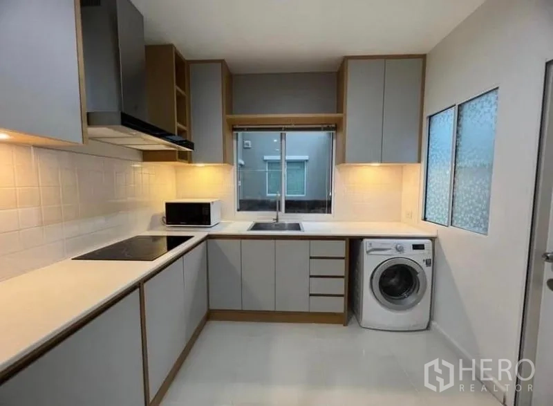 独立式住宅 出租在Suan Luang, Bangkok - L形现代厨房，内置柜体、灶台、吸油烟机和洗衣机