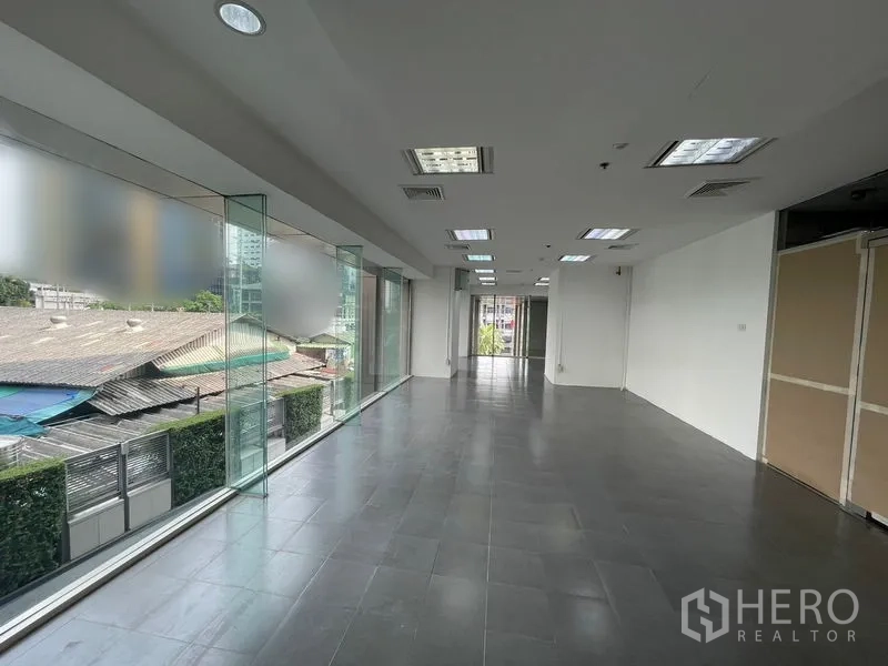 Office Space for rent - Long corridor-style office layout leading toward glass doors and street-facing windows.