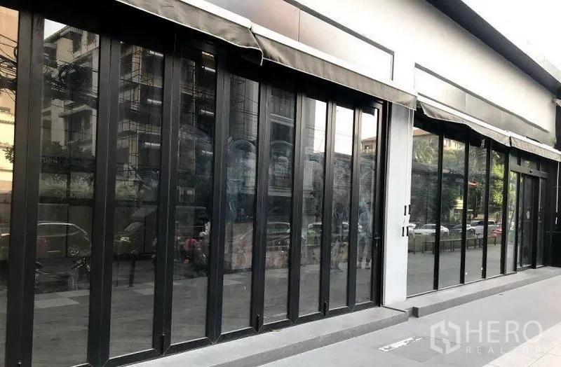 Retail Space for rent in Khlong Toei, Bangkok - Close-up of black-framed sliding glass storefront with awnings and street view in the Thonglor area.