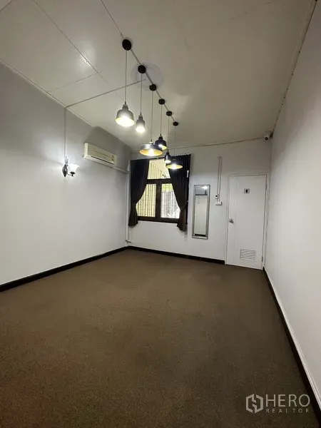 Detached House for rent in Watthana, Bangkok - Empty room with pendant lights, wall-mounted air conditioner and curtained window.