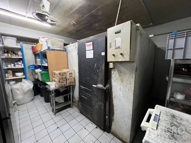 Retail Space for rent or sale in Khlong Toei, Bangkok - Storage room with walk-in freezer and shelving for supplies.