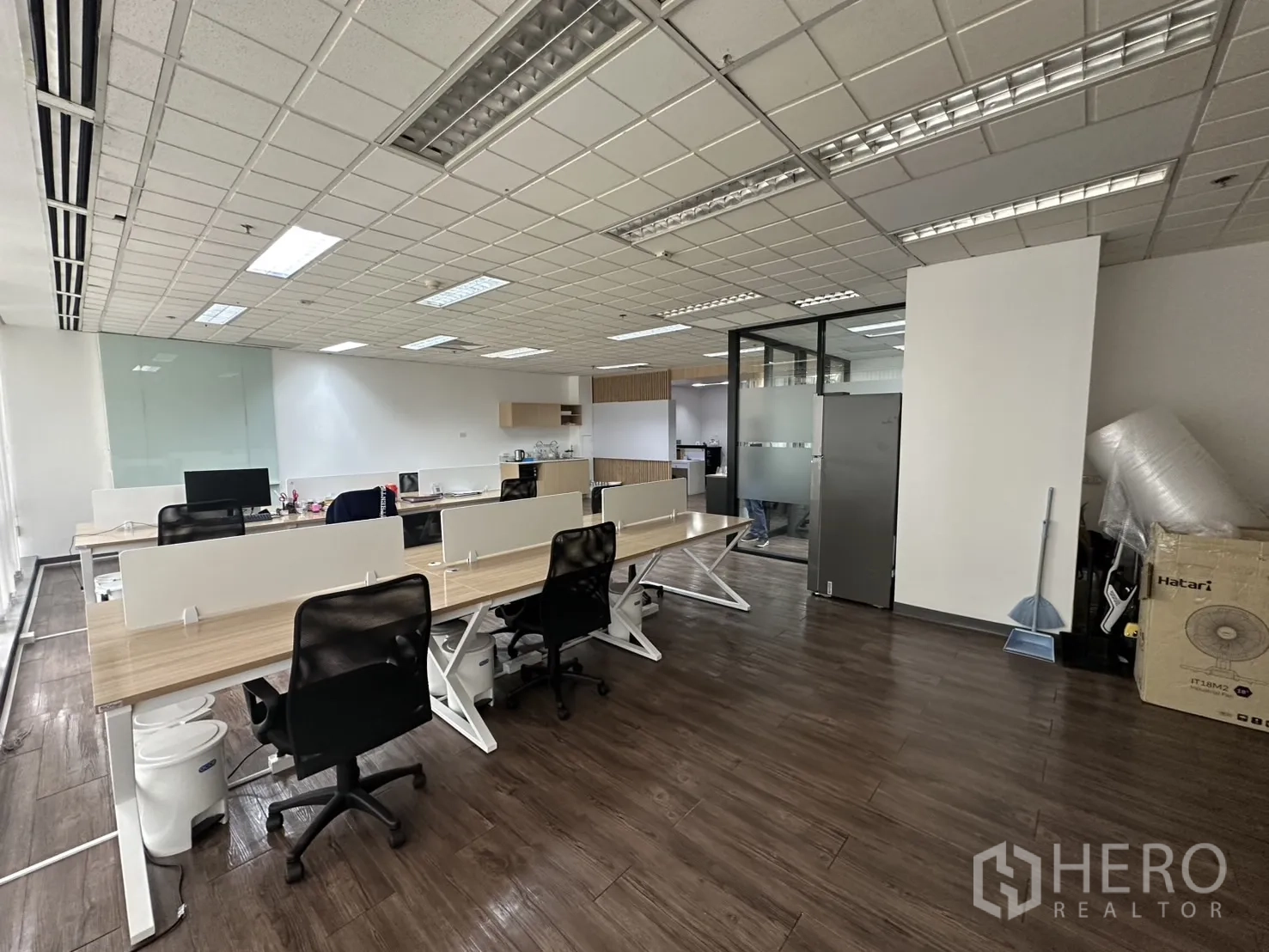 Office Space for rent - Spacious office with workstations, frosted-glass meeting room, and storage shelving.