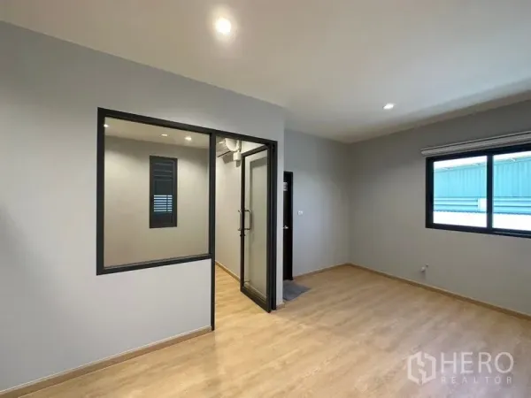 Factory for rent or sale in Lam Luk Ka, Pathum Thani - Bright office room with glass partition, wood flooring and a large window for natural light.