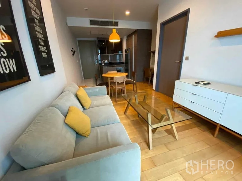 Condominium for rent in Khlong Toei, Bangkok - Open living area facing the kitchen with sofa, dining set and pendant light.
