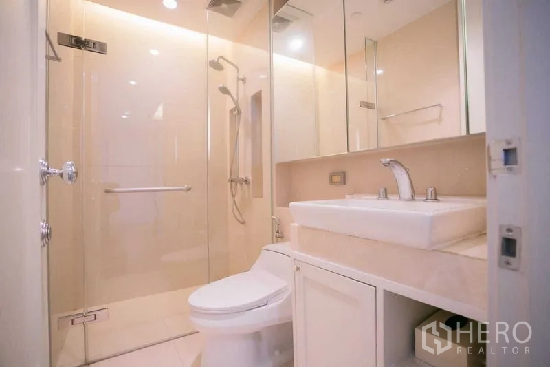 Condominium for rent or sale in Pathum Wan, Bangkok - Second bathroom with glass-enclosed shower, toilet and sleek vanity.