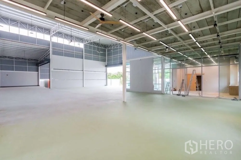 Warehouse for rent in Lat Krabang, Bangkok - Expansive production floor with LED strip lights and glass-partitioned office section.