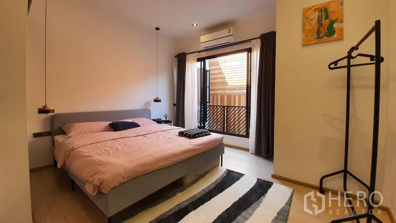 Townhouse for rent in Khlong Toei, Bangkok - Guest bedroom with balcony, pendant lights, split air-conditioning, and cozy rug.