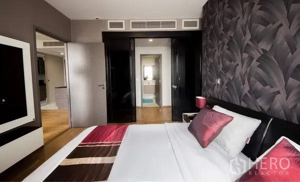 Condominium for rent in Khlong Toei, Bangkok - Contemporary bedroom with feature wall, built-in wardrobe and doorway to an ensuite bathroom in a Khlong Toei condo.