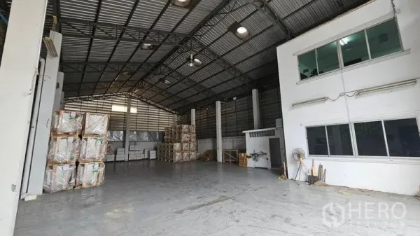 Warehouse for rent in Lak Si, Bangkok - High-clearance warehouse interior with steel truss roof, concrete floor, and attached office block.