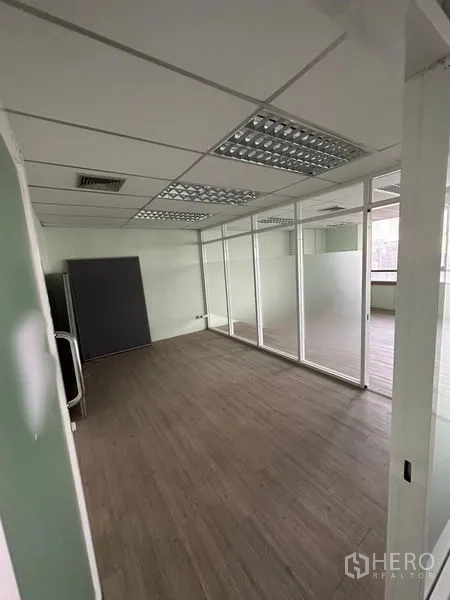 办公空间 出租 - 带玻璃隔间的独立办公区，木纹地板与格栅吊顶荧光灯。