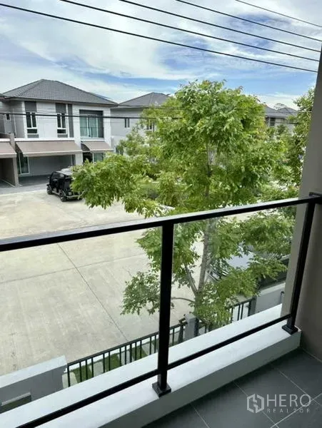 Townhouse for rent in Bang Phli, Samut Prakan - Balcony view over peaceful street with trees and neighboring townhouses.