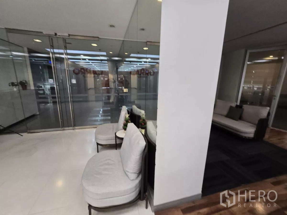 Office Space for rent in Watthana, Bangkok - Waiting nook with soft chairs beside glass double doors and dark carpet.