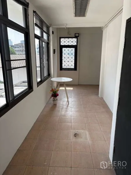 Office Space for rent in Khlong Toei, Bangkok - Bright hallway with windows and a small round table overlooking the neighborhood.
