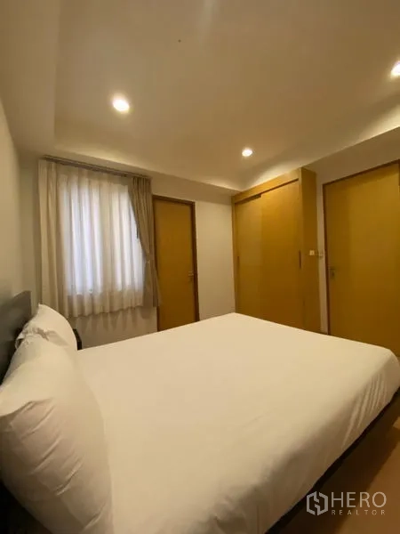Condominium for rent in Watthana, Bangkok - Second bedroom with a double bed, built-in wardrobes, and soft recessed lighting.