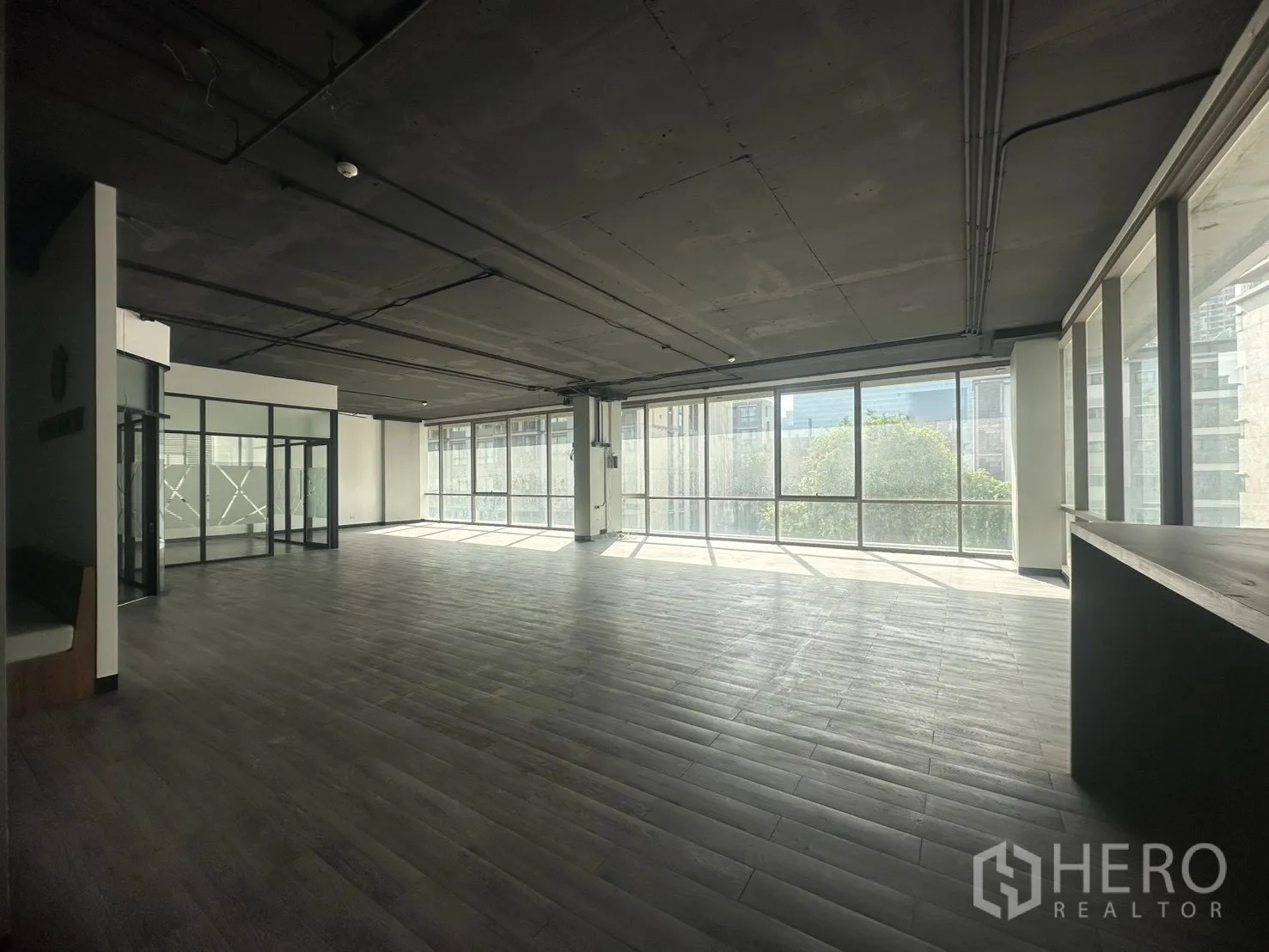 Office Space for rent in Khlong Toei, Bangkok - Panoramic office space with wall‑to‑wall windows overlooking greenery and nearby buildings.
