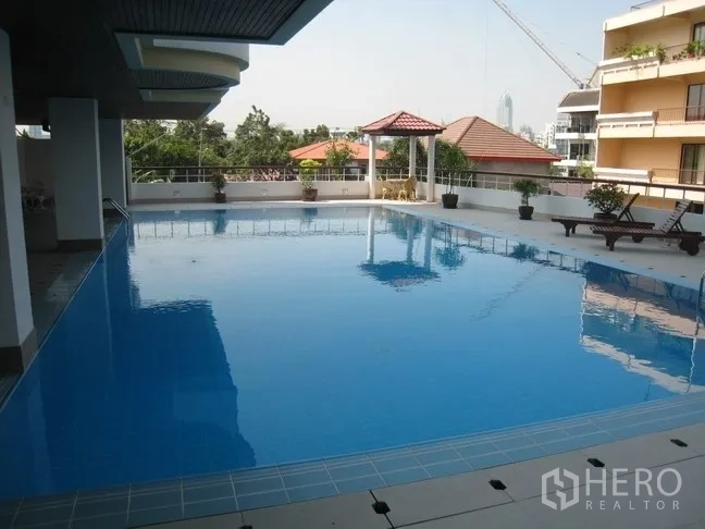 Condominium for rent in Khlong Toei, Bangkok - Large outdoor swimming pool with sun deck and city backdrop at the condominium.