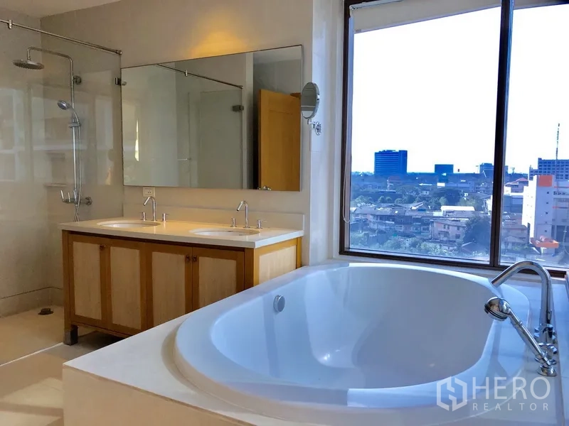 Condominium for rent in Khlong Toei, Bangkok - Luxurious bathroom featuring a large soaking tub, double vanity and separate shower next to a picture window.