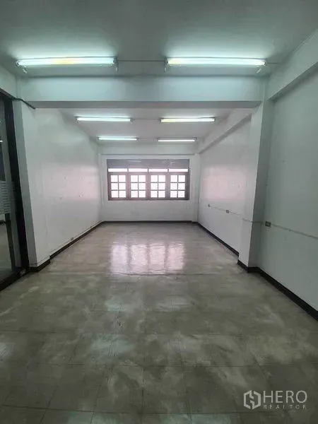 Shophouse for rent in Bang Rak, Bangkok - Long rectangular room with bright fluorescent lights, window and clean tiled floor.