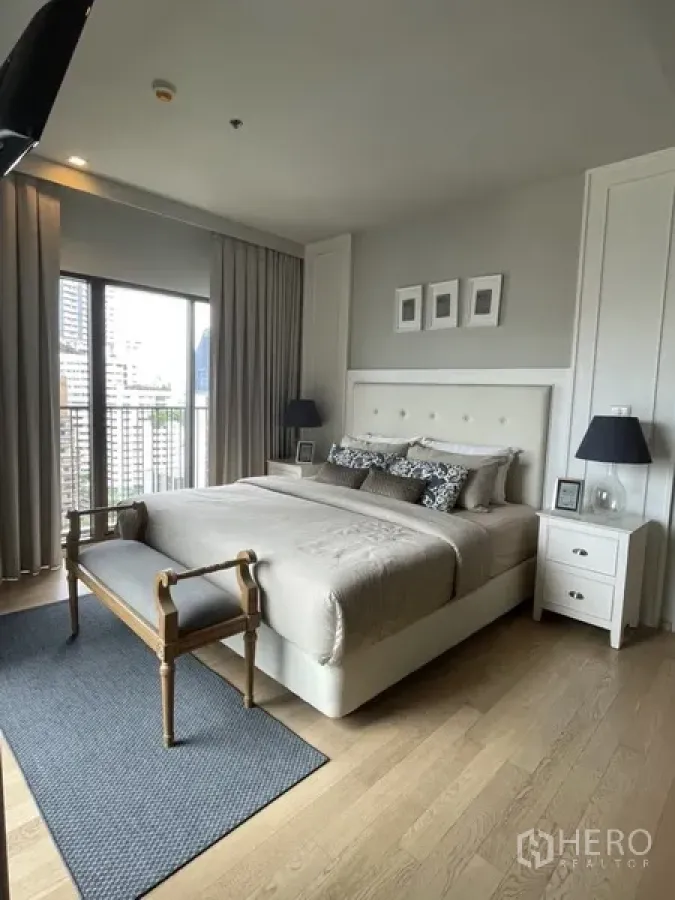 Condominium for rent in Bangkok - Spacious bedroom with king bed, wood floors, and access to a city-view balcony.