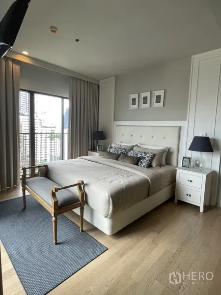 Condominium for rent in Bangkok - Spacious bedroom with king bed, wood floors, and access to a city-view balcony.