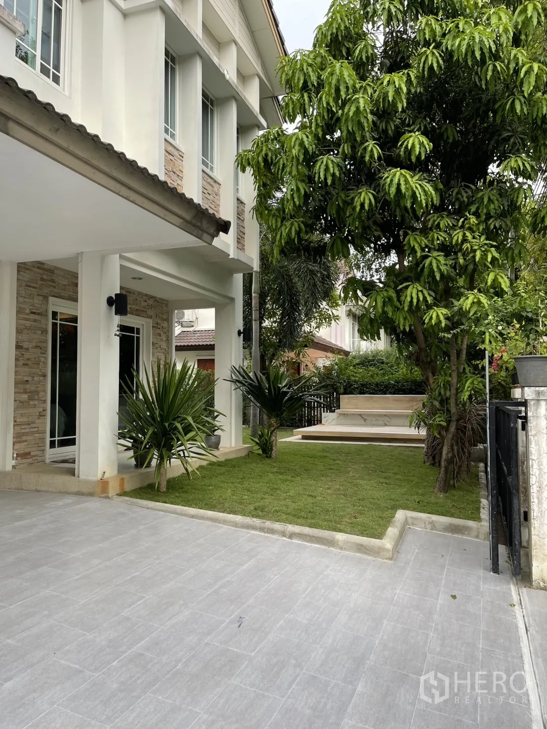Detached House for rent in Bang Kapi, Bangkok - Tiled driveway with a small landscaped front lawn and large shade tree beside the entrance.