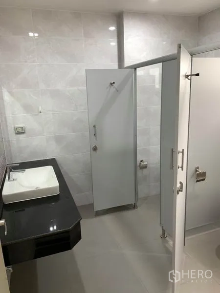 Home Office for rent or sale in Bang Na, Bangkok - Modern restroom with vanity, tiled walls and private cubicles.
