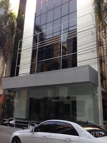 Office Space for rent in Bang Kapi, Bangkok - Modern glass-façade office building with a clear ground-floor entrance and palm trees along the frontage.