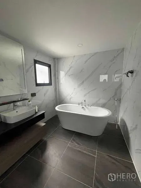 Detached House for rent in Mueang Nonthaburi, Nonthaburi - Spacious bathroom with a freestanding bathtub, vanity and marble-effect walls.