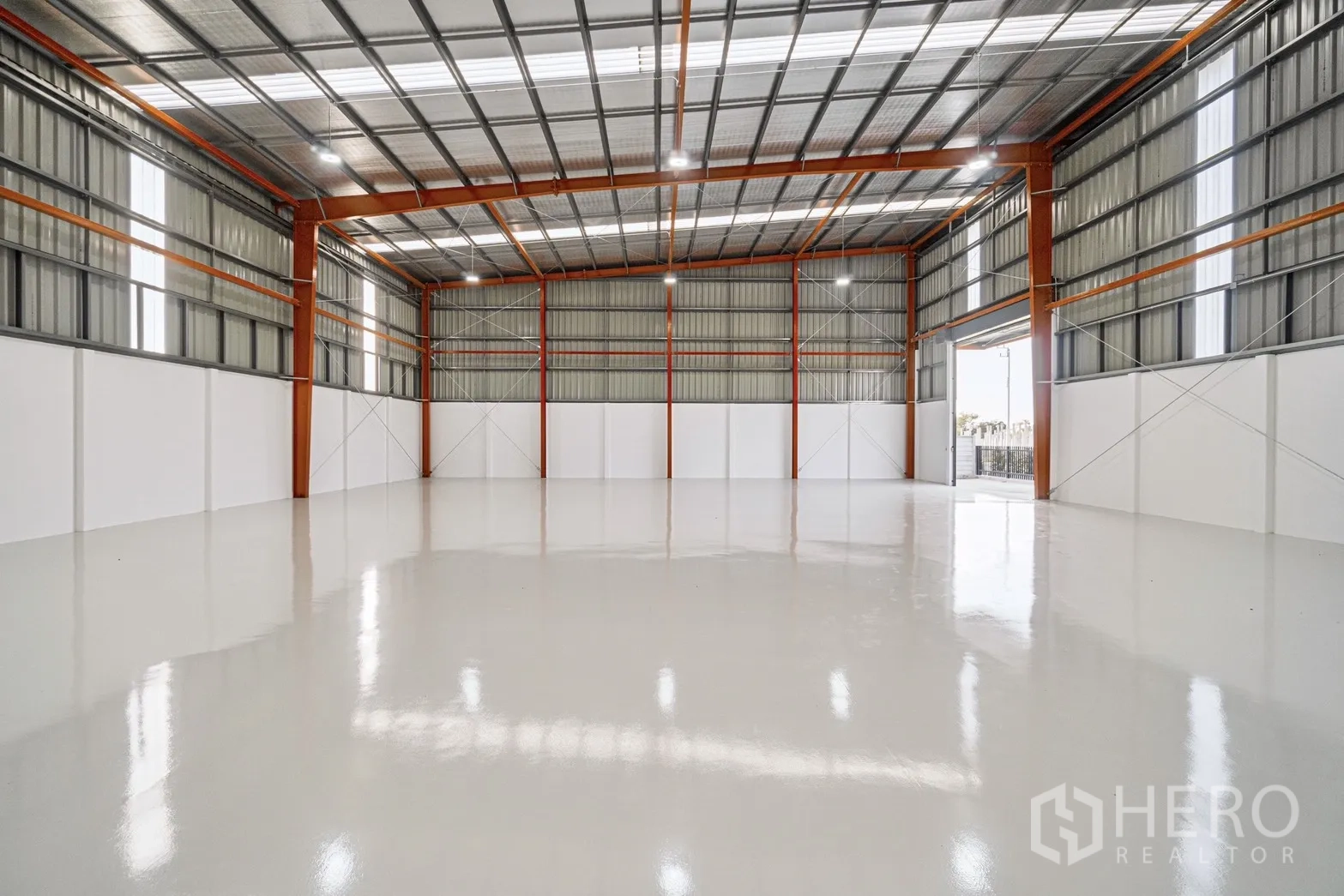 Factory for rent or sale in Lam Luk Ka, Pathum Thani - Open production space with skylight panels, bright lighting and a large roller shutter.