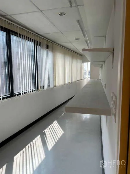 Office Space for rent in Khlong Toei, Bangkok - Bright corridor with full-height windows, vertical blinds, and floating wall shelves.