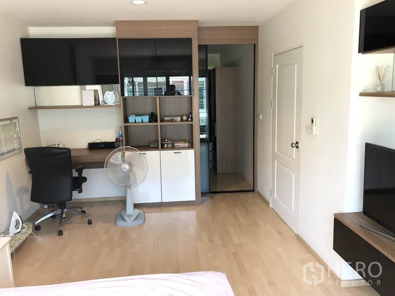 Townhouse for rent or sale in Suan Luang, Bangkok - Bedroom with wood flooring, built-in desk, shelving and wardrobe in neutral tones.