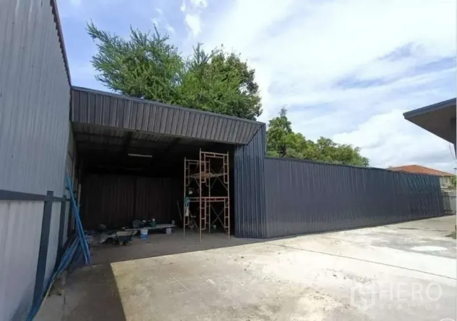 Warehouse for rent in Prawet, Bangkok - Front view of black steel warehouse with large entry and ample parking area.