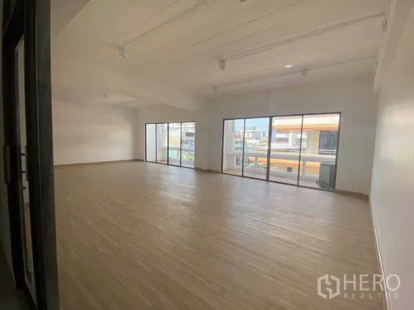 Office Space for rent in Watthana, Bangkok - Bright open-plan office with wood-look flooring and full-height sliding glass doors overlooking Phra Khanong.