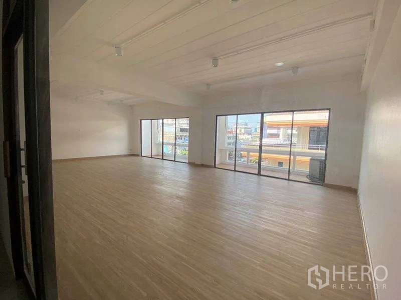Office Space for rent in Watthana, Bangkok - Bright open-plan office with wood-look flooring and full-height sliding glass doors overlooking Phra Khanong.