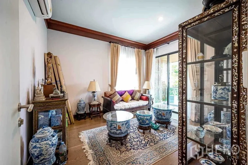 Detached House for sale in Prawet, Bangkok - Elegant sitting room with glass display cabinet and Thai ceramic decor by sliding doors.