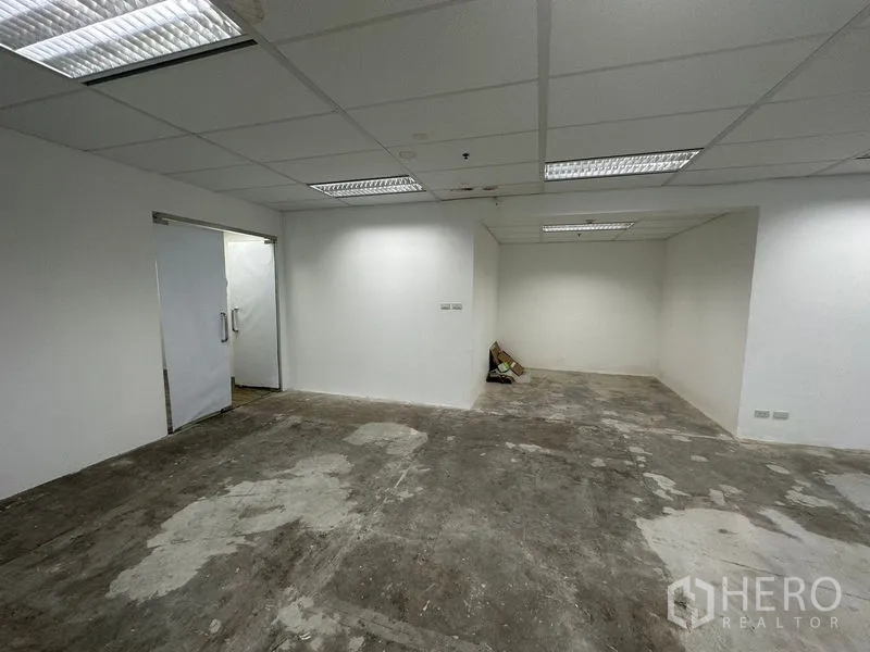 Office Space for rent - Unfurnished office room with white walls, double doors, grid ceiling and fluorescent lights, ready for fit-out.
