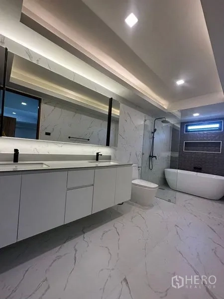 独立式住宅 出租在Suan Luang, Bangkok - 宽敞主浴室，双洗手台、独立浴缸与玻璃淋浴，大理石饰面。