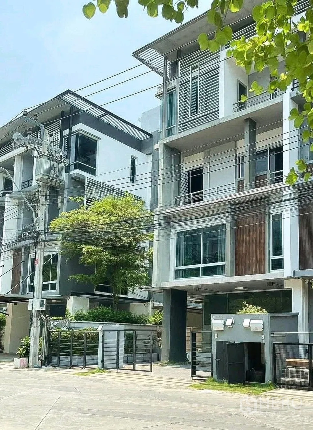 Home Office for rent or sale in Wang Thonglang, Bangkok - Street view of contemporary townhouse-style buildings and greenery.