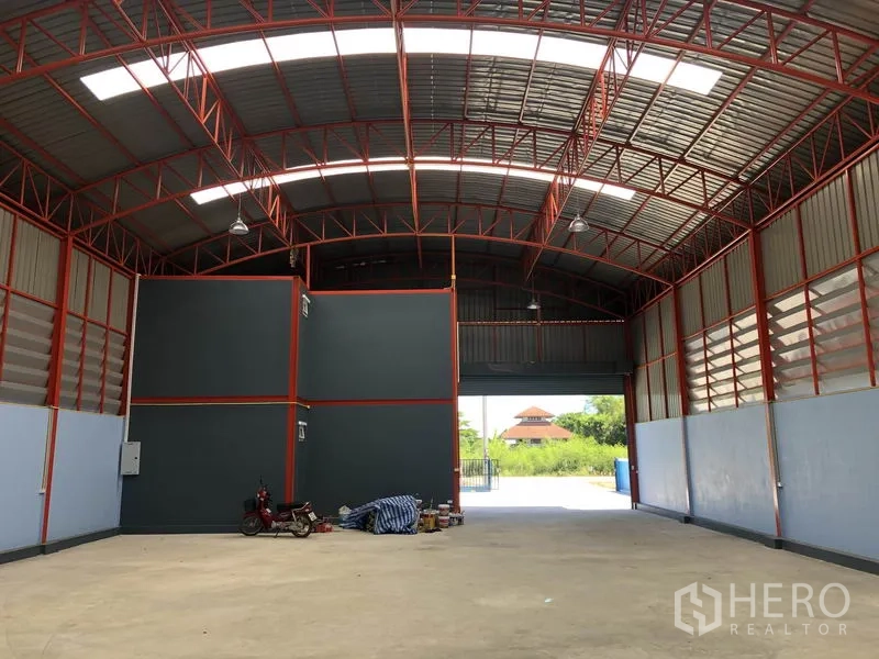 Warehouse for rent or sale in Sai Noi, Nonthaburi - Interior view toward the entrance roller shutter with clear-span floor and ventilation panels.