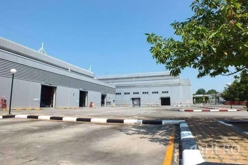 工厂 出售在Rayong - 两栋灰色仓库之间的宽大卡车回转场，设有装卸口与标线路缘。