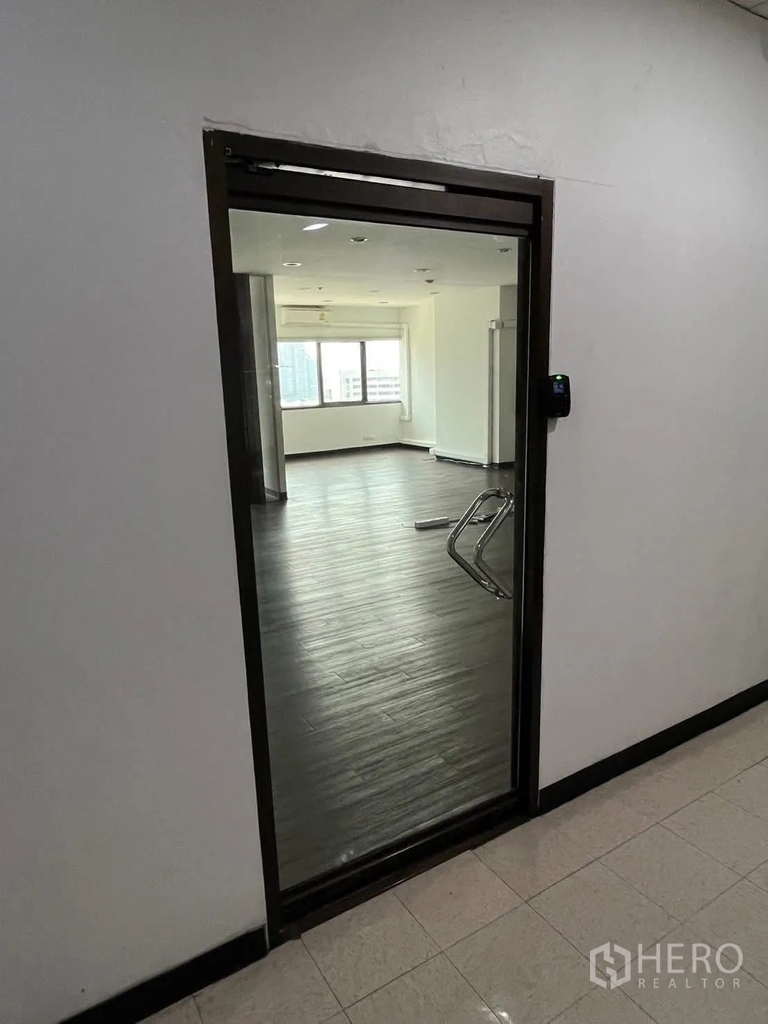 Office Space for rent in Watthana, Bangkok - Glass entry door with access control opening to a bright office with wood floors.