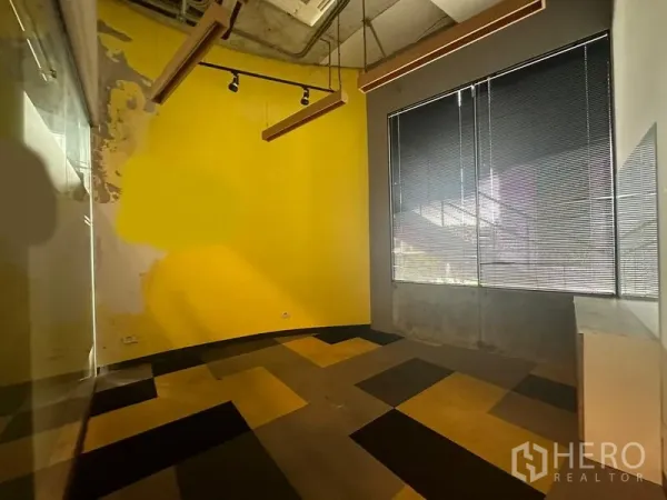 Office Space for rent - Private office with a yellow accent wall, large window with blinds and linear lighting.